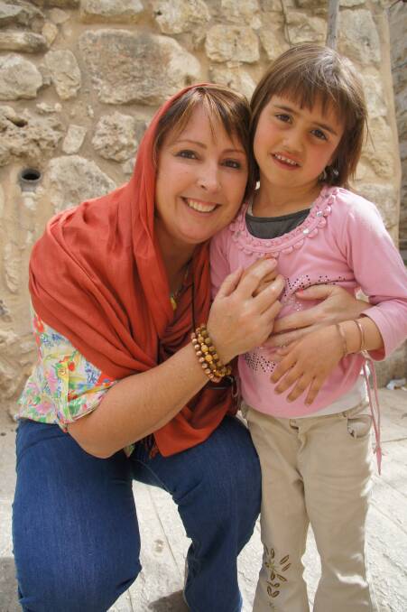 Kay Danes poses for a photograph with a young girl in Hebron, Palestine in 2013.