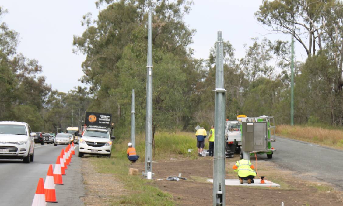 Watch your speed: Workers install the controversial point-to-point speed cameras on the Mount Lindesay Highway in July. The cameras will be switched on in November. Photo: Georgina Bayly.