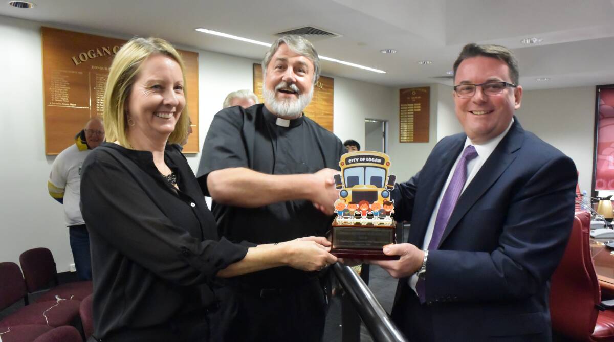CHAMPION: Linda Revill and Rev Geoff Hoyte present Logan mayor Luke Smith with the Golden Bus award at Monday's budget meeting. Photo: Christine Rossouw. 