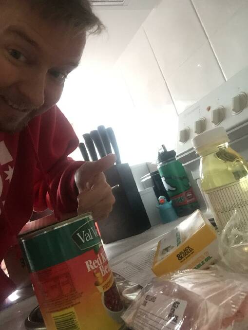 Journalist Joshua Paterson with the items in the refugee ration pack including a can of red beans, small bags of rice and lentils and chick peas,a tin of sardines and a small bottle of vegetable oil and some coupons for flour.