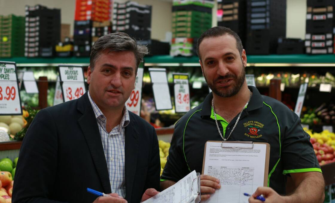 SIGN: Logan MP Linus Power inspects the petition with Olley's Orange Country Market's Steve Habchi. Photo: Supplied
