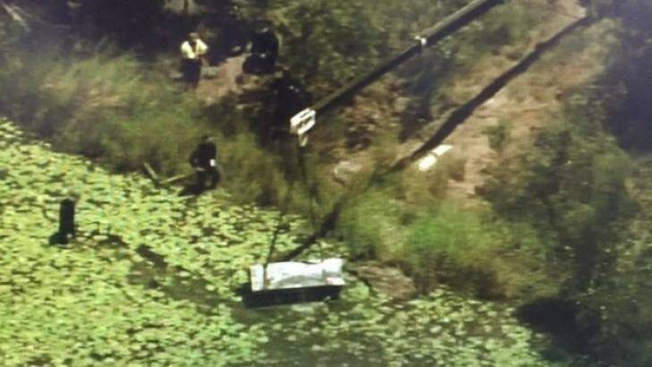 A crane lifts a metal box from a dam at Logan as police search for two bodies. Photo: Nine News Brisbane/Twitter