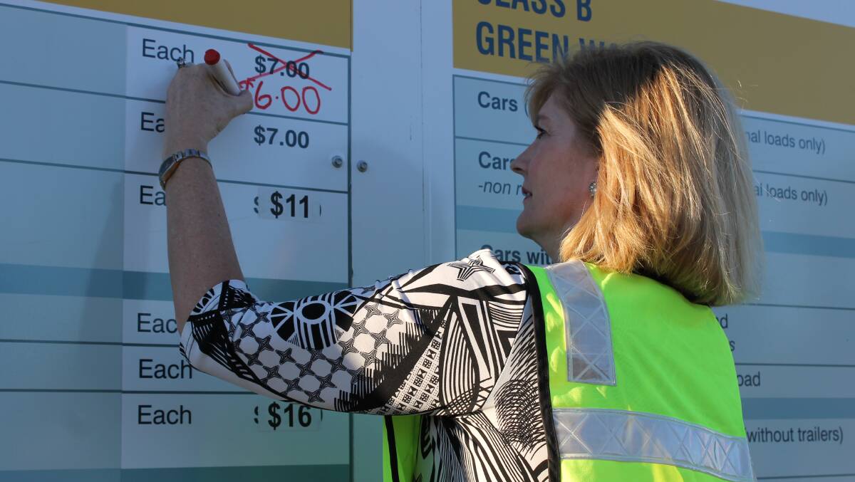 Logan Mayor Pam Parker updates the fee information board at Browns Plains tip to reflect savings from the repeal of the carbon tax.