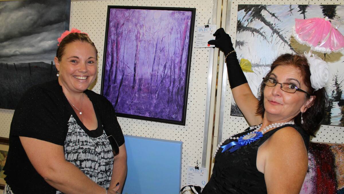 Julie Zapotezny purchases a painting as a gift for her sister, with Quota member Francis Ziliotto's help.