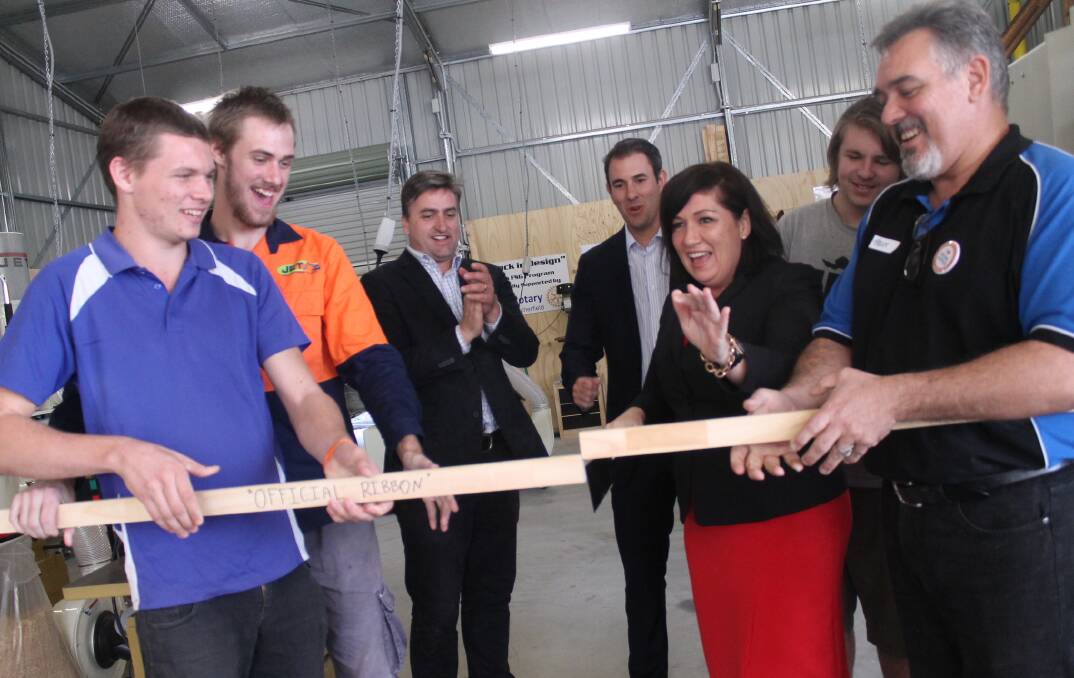 Rock in Design participants Daniel Roope, Rhys Sharp and Ryan Eyears (back right) with Member for Logan Linus Power, Member for Rankin Jim Chalmers, Housing and Public Works Minister Leeanne Enoch and Rock in Design coordinator Trent Powrie saw through the 'official ribbon' to officially open the program.