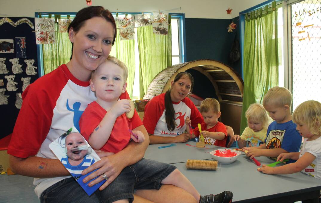 Kim Beadel with and picture of son Zach and son Mason, 2, Flagstone Goodstart Early Learning centre director Joanne Burns and junior kindergarten children Coen Burns, Grace Kingdom, Thomas Ruhland and Ruby Wallace are helping raise funds for HeartKids this week.