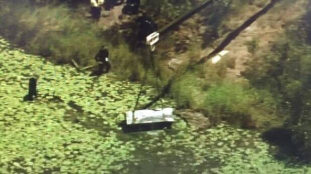 A crane lifts a metal box from a dam at Logan as police search for two bodies. Photo: Nine News Brisbane/Twitter
