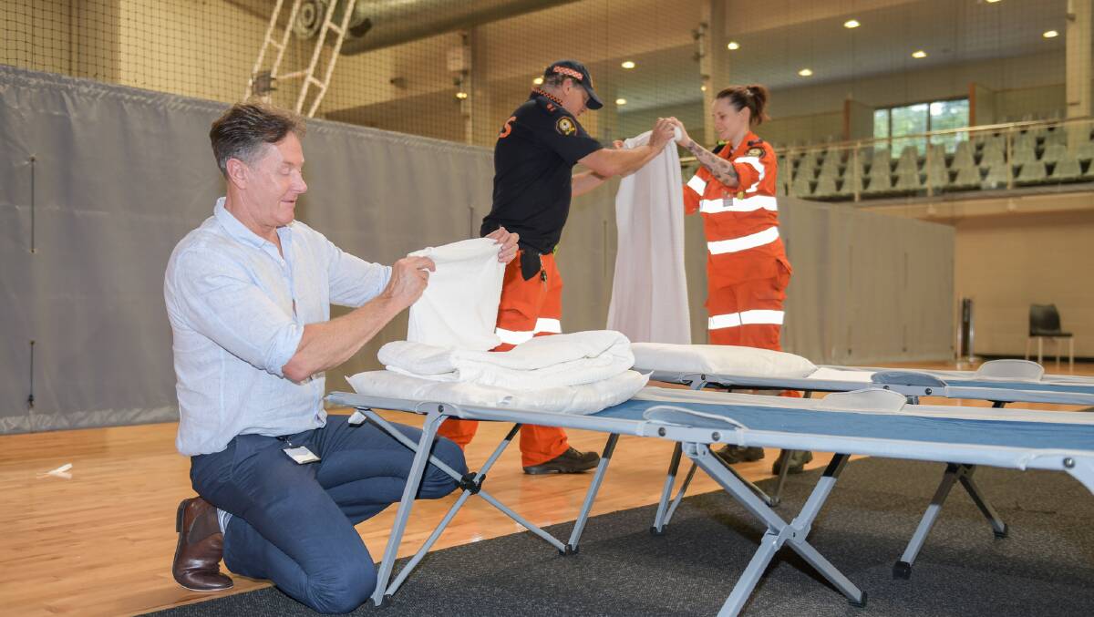 EVACUATION CENTRE OPENS: City of Logan Mayor Darren Power helping prepare beds at the Logan Metro Sports & Events Centre in Crestmead this afternoon. Picture: supplied