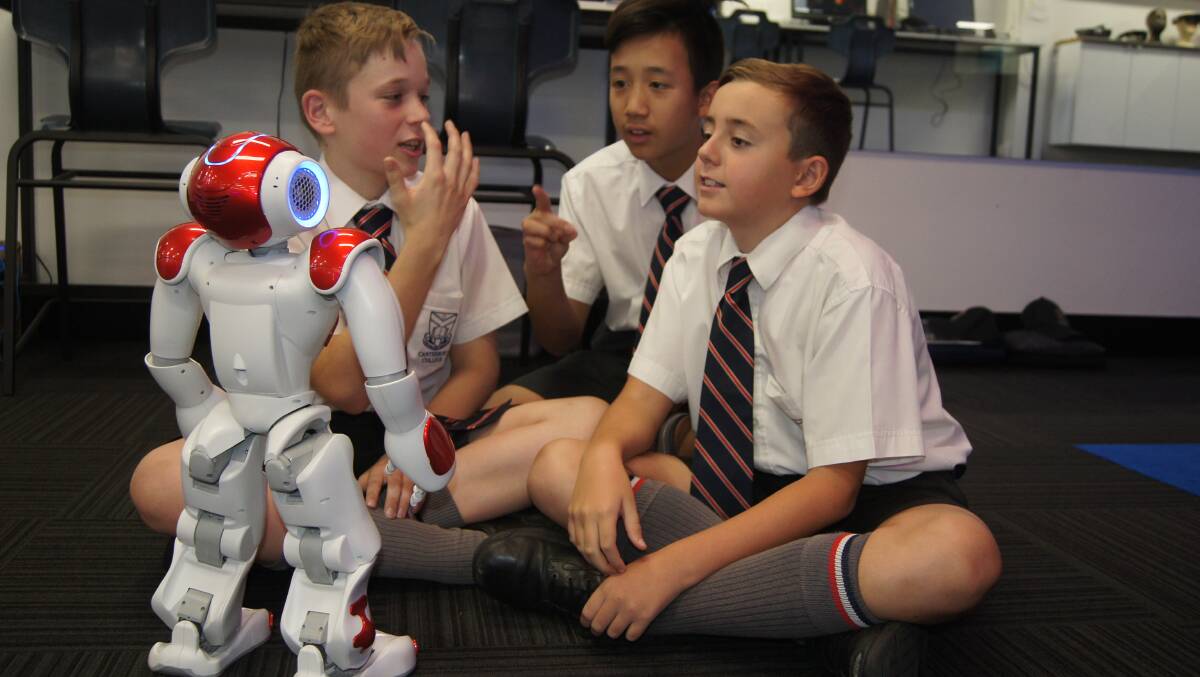 Canterbury College year seven students Ashton Frylink, Andrew Owng and Geoffrey Bladon interact with digital hub robot Nao.