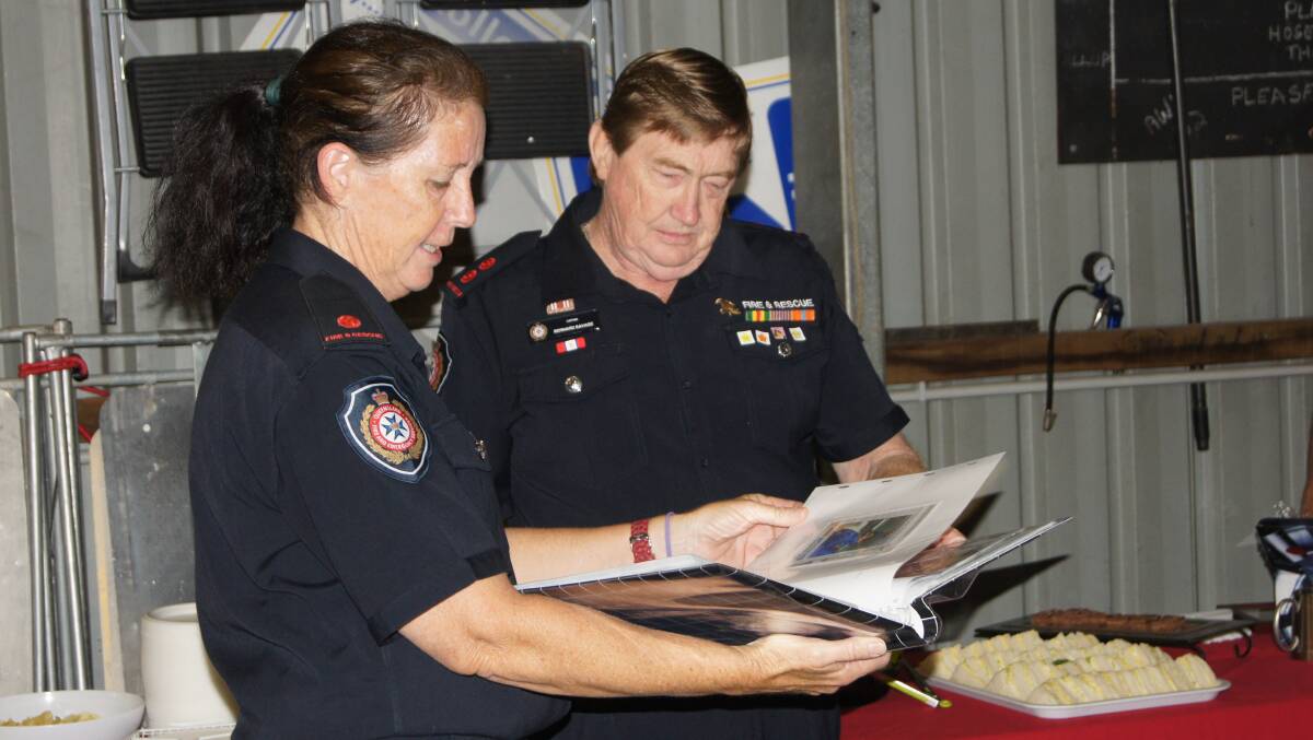 Jimboomba firefighter Gail Steppens presented Bernie Savage with a photo album to mark his time on the job. Photo: Jacob Wilson