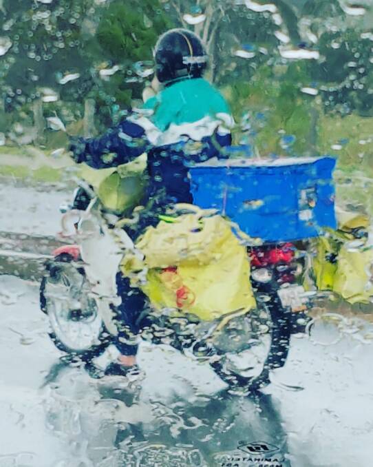 RAIN OR SHINE: A postie on the road during the wet weather. Heavy rains are expected across south-east Queensland over the weekend. Photo: Louisa Angel