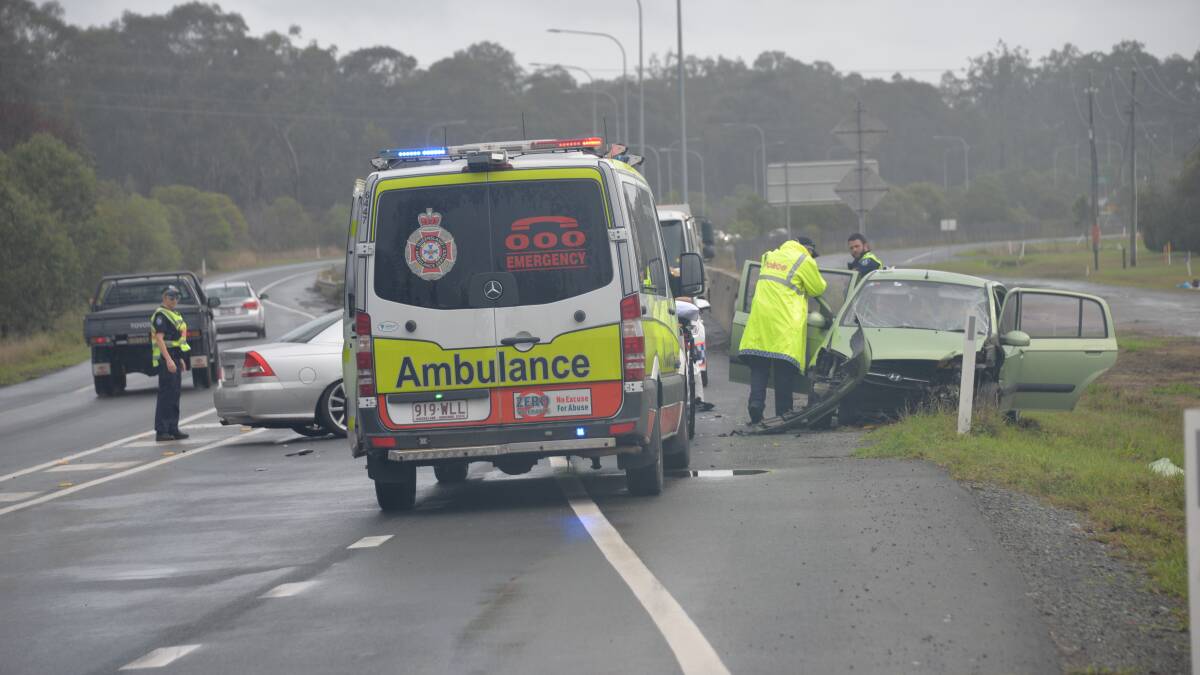 CAR CRASH: Police and ambulance officers at the head-on crash north-east of Jimboomba on the Mount Lindesay Highway this morning. Photo: Brian Williams
