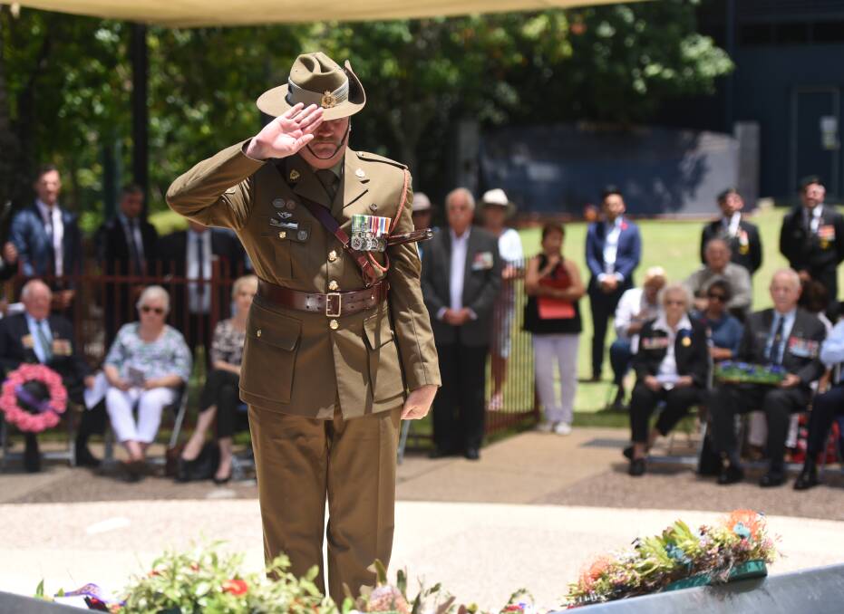 Lest We Forget: Peter Mitchell salutes the fallen at Greenbank's Remembrance Day service. Photo: Matt McLennan