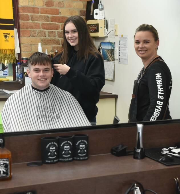 STAR: Bree Connell gives brother Jake a haircut as Murphy's Barber owner Toni Allen watches on. Photo: Matt McLennan